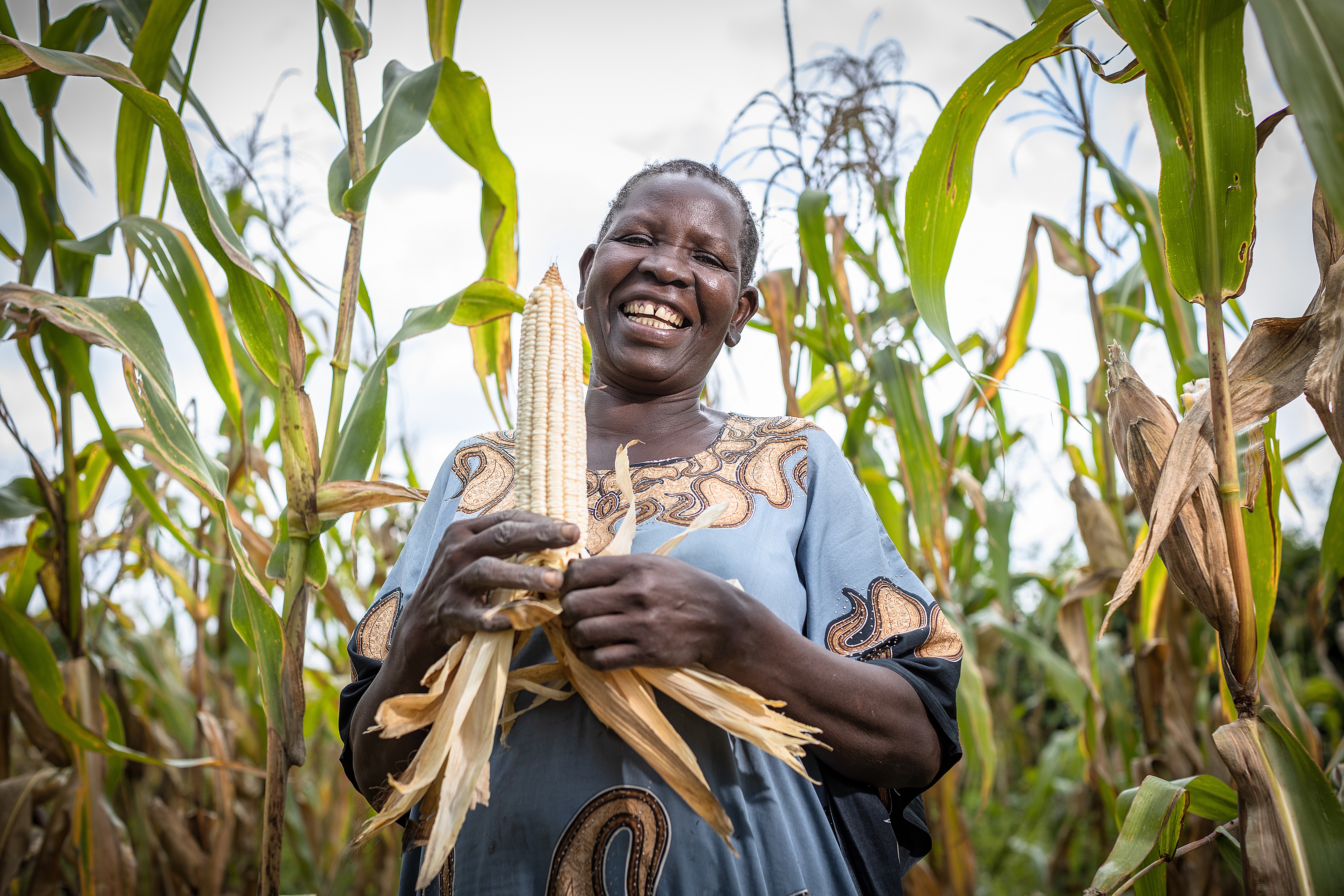 A Ugandan woman agribusiness entrepreneur inspecting produce at a rural cooperative